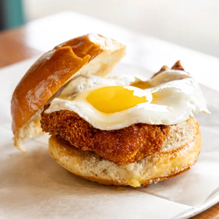 Our scratch-made menu features The Chicken & The Egg, a fried chicken sandwich with an egg sunny side up, hot honey drizzle, on a toasted potato bun