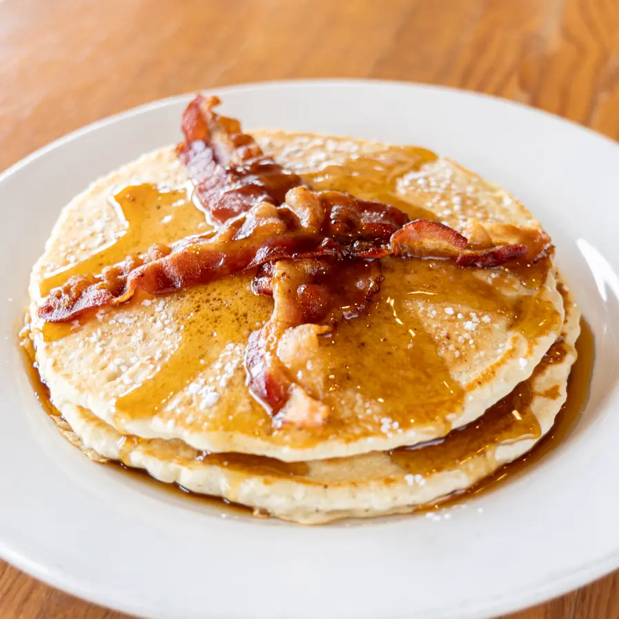 Pancakes and bacon with maple syrup and powdered sugar